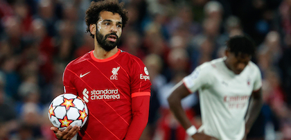 Mo Salah wears his Liverpool kit on the pitch while holding a Champions League ball