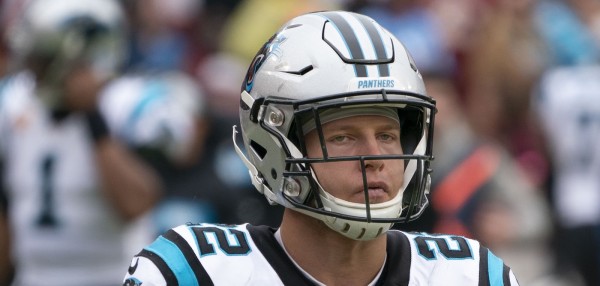 Christian McCaffrey of the Carolina Panthers looks grumpy while on the field with his Panthers uniform and helmet on.