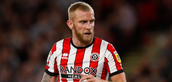 Oli McBurnie looks on during a game while wearing a red and white Sheffield United shirt